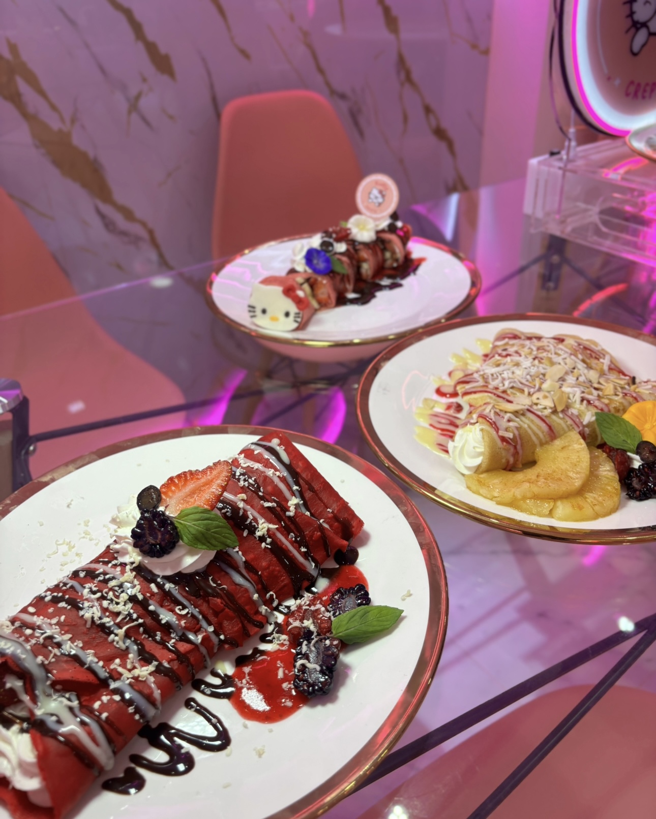 Crepa red velvet y crepa de piña sobre mesa de cristal rosa